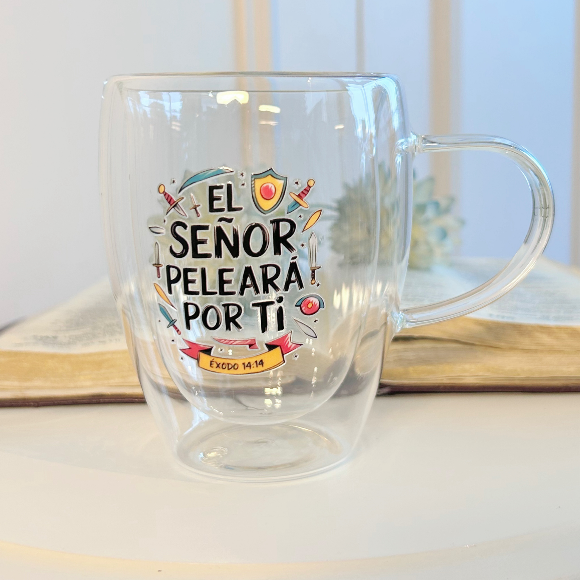 Taza de 350ml con mensaje bíblico de fortaleza. Incluye caja rosada o negra. Regalo cristiano con propósito y protección.